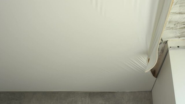 Process of dismantling of stretch suspended ceiling in flat, closeup view. Interior, indoors.