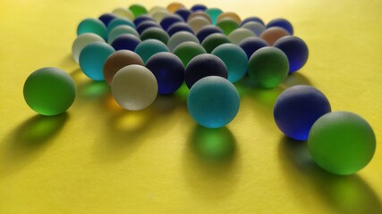 Blue and green glass frosted balls on a yellow surface. Partially defocused. Tactile play or...