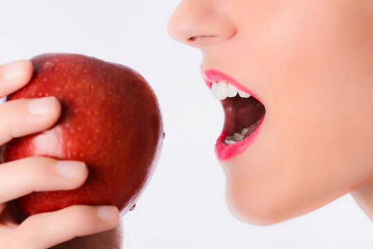 Close up of beautiful young woman mouth biting a red apple.