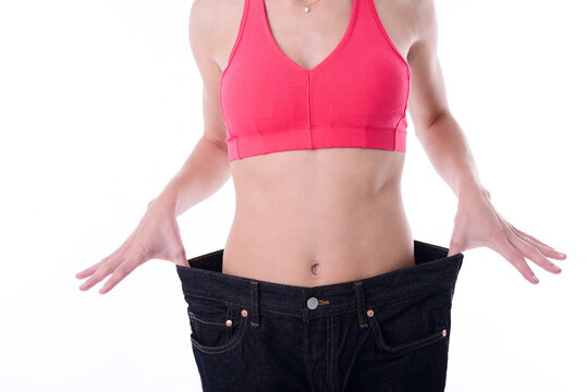 Beautiful young woman trying oversize pants after diet weight loss program.