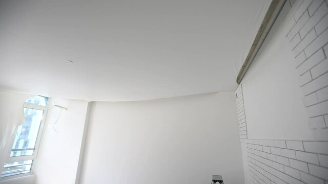 installs a canvas of white stretch ceiling in the room of the apartment
