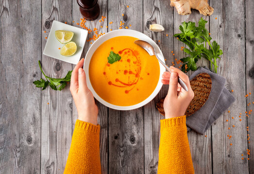 Top View Of Unrecognisable Woman In Orange Sweater Eating Warm And Spicy Winter Lentil Soup