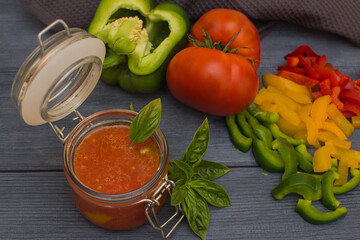 Lecho is a traditional Hungarian dish. Stewed peppers in tomato sauce on a dark gray wooden background. Home preparation of canned peppers in tomato sauce.
