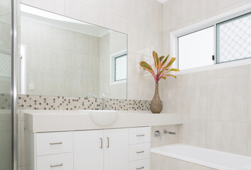 New modern bathroom in new house with tiled walls, stone bench top and bathtub