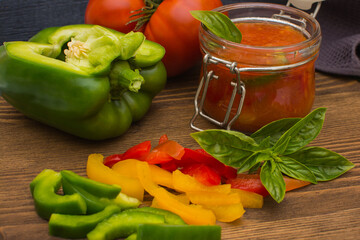 Lecho is a traditional Hungarian dish. Stewed peppers in tomato sauce on a dark gray wooden background. Home preparation of canned peppers in tomato sauce.