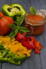 Lecho is a traditional Hungarian dish. Stewed peppers in tomato sauce on a dark gray wooden background. Home preparation of canned peppers in tomato sauce.