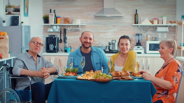 Extanded family and immobilized grandfather having a video call in their modern, luxury kitchen during dinner. Pov online internet modern, chatting, communication, chat conversation call via webcam.