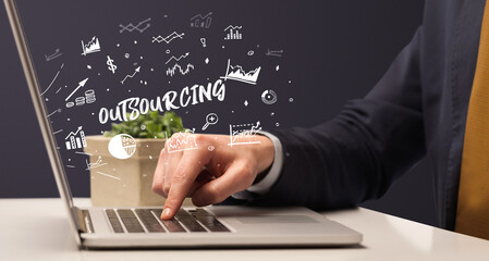 Businessman working on laptop with OUTSOURCING inscription, modern business concept