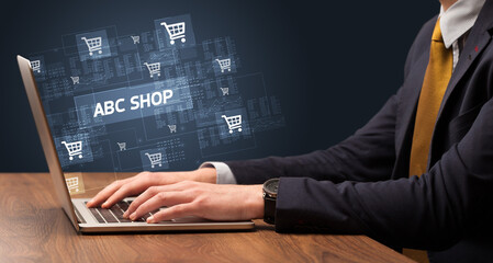 Businessman working on laptop with ABC SHOP inscription, online shopping concept