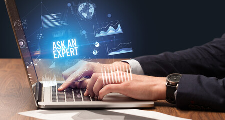 Businessman working on laptop with ASK AN EXPERT inscription, new business concept