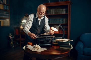 Elderly writer inserts paper into the typewriter
