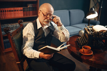 Elderly writer reads work at vintage typewriter