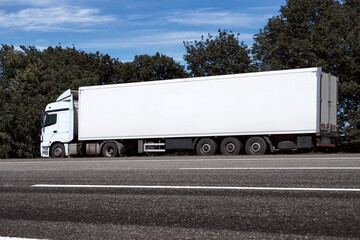 truck on the road, side view, empty space on a white container - concept of cargo transportation, trucking industry