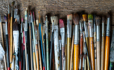 Mixed painting brushes lying on the wooden background.