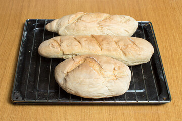 Three different freshly baked homemade loaves of bread on a band on the kitchen table. Steps to make bread at home.