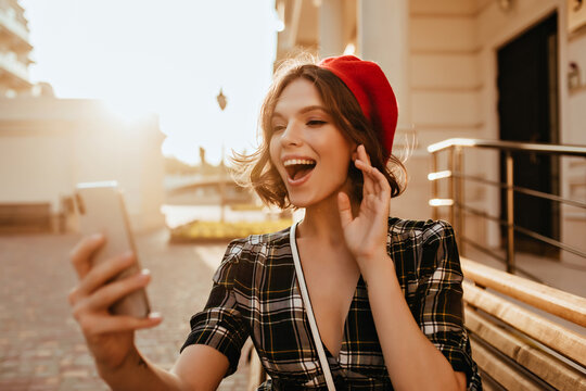 Inspired white woman with short haircut having fun in autumn day. Outdoor photo of fascinating french female model in beret holding smartphone.