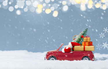 Santa Claus in Red car delivering christmas tree and presents at snowy background. Christmas background.