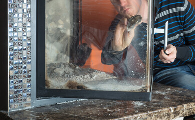 Man wipes the dirty glass of fireplace