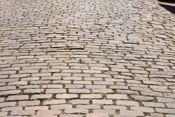 Cobblestone with green grass sprouting in Colmar, texture, France during summer time.