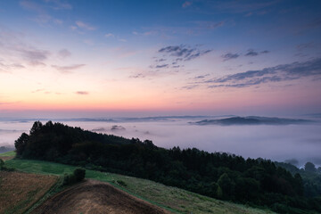 Naklejka na ściany i meble Beautiful Morning at Countryside. Rolling Hills in Morning Fog. Pink Sky. Blue Hour