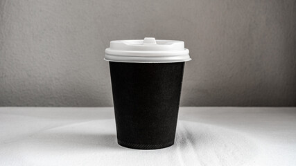 Black paper cup of coffee on the table