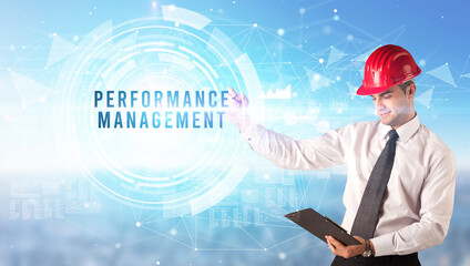 Handsome businessman with helmet drawing PERFORMANCE MANAGEMENT inscription, contruction business concept