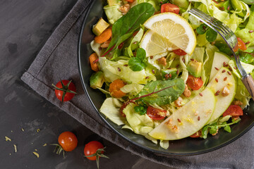 Salad. Spring vegetable salad. Fresh vegetable salad with tomatoes, apple, nuts, seeds and lemon. Olive oil pouring into bowl of salad