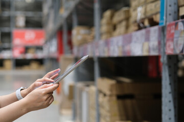close up hands using tablet with blurred goods shelf background. warehouse, store concept 