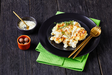Cauliflower cheese casserole on a black plate