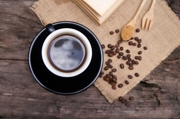 Black coffee and coffee beans on a brown wooden table.