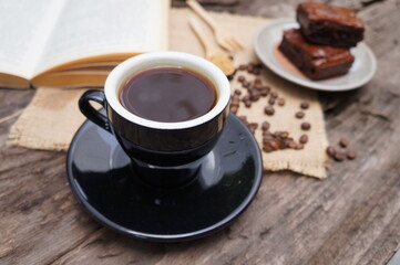 Black coffee and coffee beans on a brown wooden table.