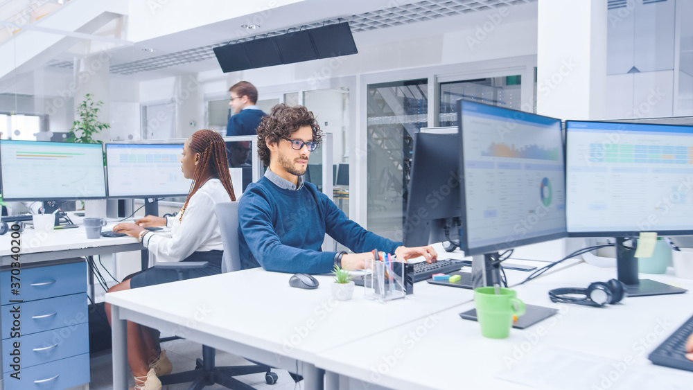 Poster in the big busy corporate office portrait shot of a beautiful male manager sitting at his desk and u