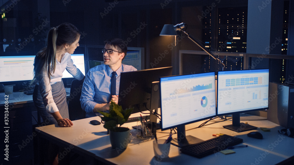 Aufkleber Late at Night in Modern Office: Office Worker Sitting and Working at His Desktop Computer, Discusses Problem Solution wit Project Manager, They Look at Each Other.