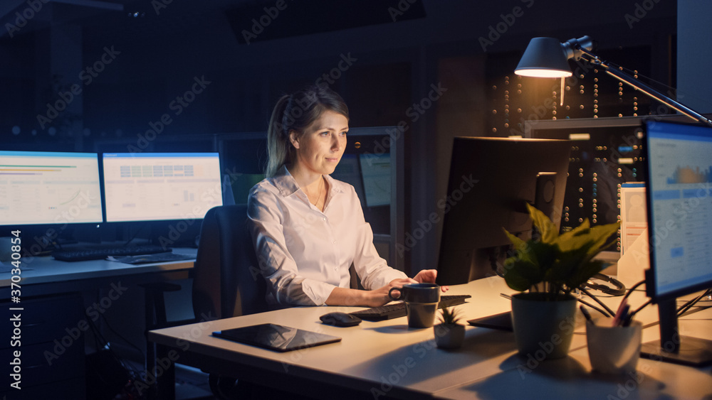 Poster working late at night in the office: businesswoman using desktop computer, analyzing, using document