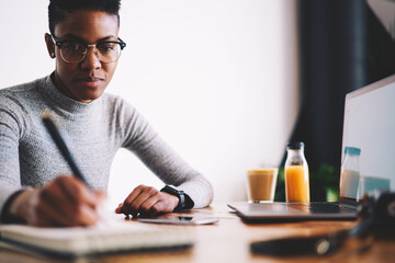 Young experienced administrative manager providing organization in office making checklist and schedule for staff members monitoring productivity of employee using laptop computer and wireless network