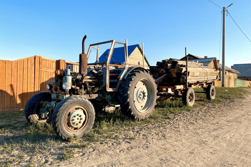 Obraz premium Old rusty abandoned agricultural tractor in a grass field tractor with trailer