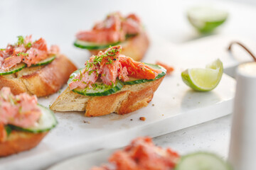 Toasts with fresh cucumber and smoked salmon served with lime shavings