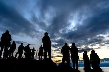 Faceless group of people on top of a mountain watching sunset, silhouette of group of people taking pictures outside during sunrise or sunset