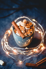 Hot chocolate with marshmallows and cinnamon in blue ceramic cups on a table. The concept of cozy holidays and New Year.