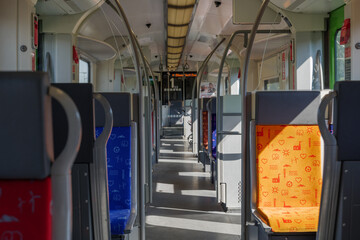 Interior view of a corridor inside passenger trains with colourful fabric seats of German railway train system. Empty vacant passenger car inside the train.
