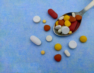 Pills in spoon kept on blue paper for Daily dose, copy space Selective focus