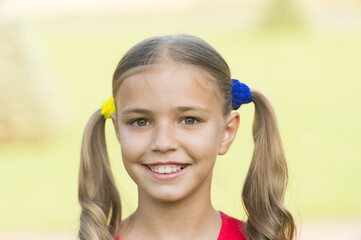 Cheerful little girl adorable ponytails hairstyle outdoors, positivity concept