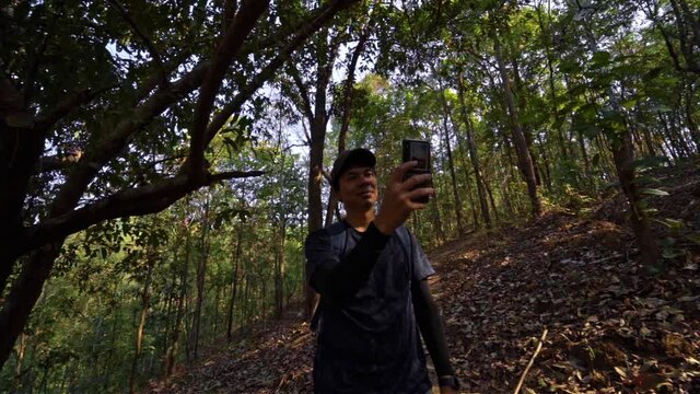 slow motion video local travel hiking man use phone take picture in tropical rain forest on springtime