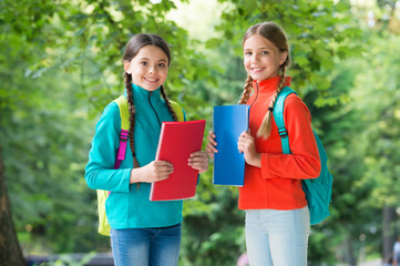 Fototapeta premium Schoolgirls with backpacks and textbooks in forest, exploring nature concept