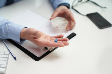 Healthcare worker holding a blue pill in his hand