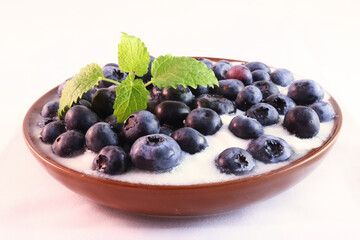 Closeup of blueberries in white yogurt with piece of mint
