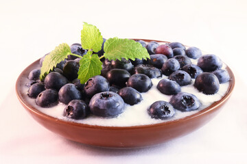 Closeup of blueberries in white yogurt with piece of mint