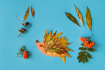 little child making autumn decoration from leaves and forest berries. Children's art project. DIY...