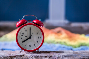 Red analog clock on cement flor in a house with snad colorful and show time 8.00 a.m