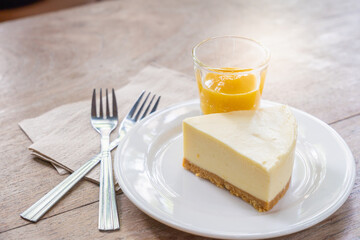 Cheese cake with lemon sauce in small glass on white disk put on wooden desk